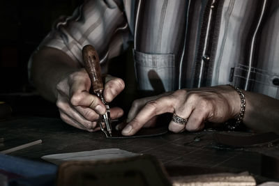 Midsection of man working with leather at table in workshop