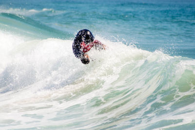 Surfer in sea on sunny day