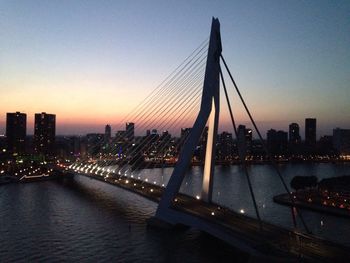 Suspension bridge over river at sunset