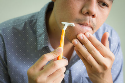 Close-up of man shaving against white background