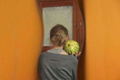 Rear view of woman standing against orange wall