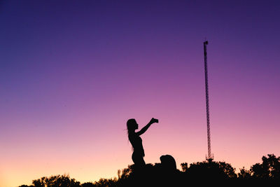 Silhouette man and woman standing against sky during sunset