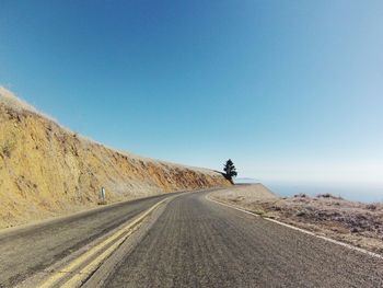 Road by mountain against clear blue sky