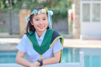 Portrait of smiling young woman standing by railing