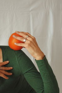 Midsection of woman holding orange fruit