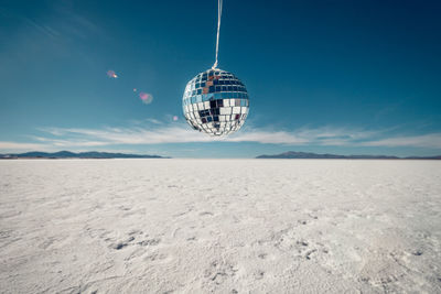 Disco ball over salt flat against blue sky