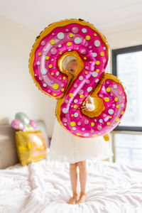 Low section of woman with balloons on bed at home