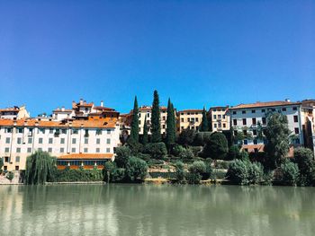 Buildings by river against blue sky. bassano del grappa- italy