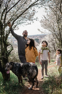 Father with three daughters and a dog watching blooming trees in the park