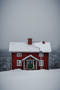 White house on snow covered field against sky