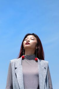 Low angle view of woman looking away against blue sky