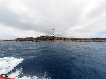 Lighthouse by sea against sky