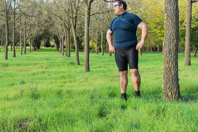 Man standing on grassy field against bare trees