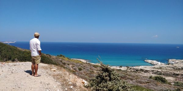 Rear view of man looking at sea shore against sky