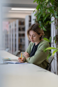 Academic career. female university professor taking notes in day planner while sitting in library