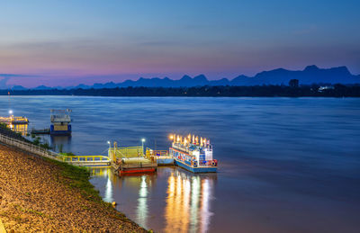 Tourist boats docked along the mekong river during twilight in nakhon phanom province, thailand