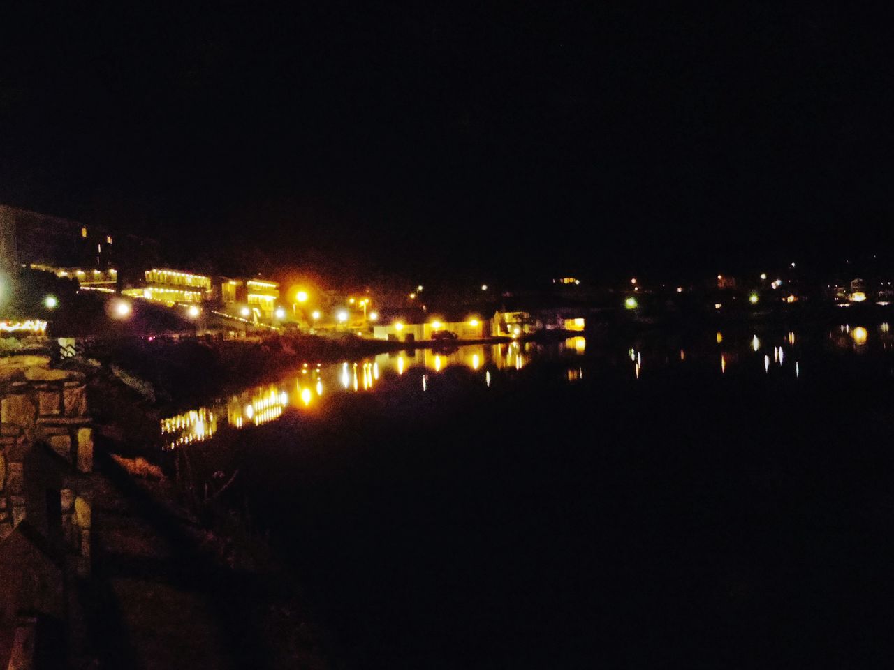 ILLUMINATED BRIDGE OVER RIVER AT NIGHT