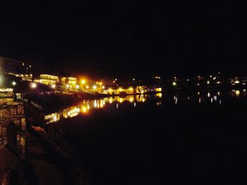 Illuminated bridge over river against sky at night