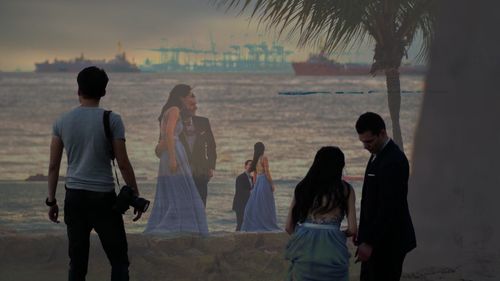 People on beach against sky during sunset