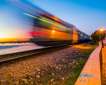 Train on railroad tracks against sky during sunset