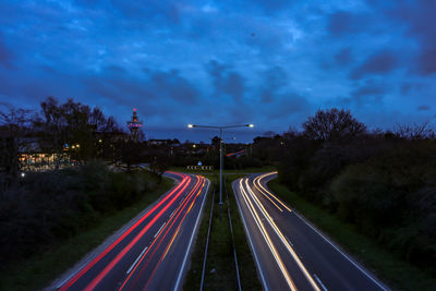 Light trails on road against sky at night