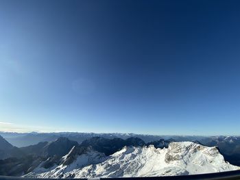 Scenic view of snowcapped mountains against blue sky