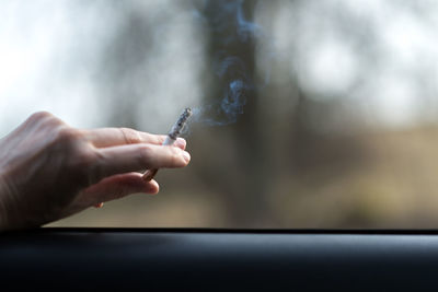 Cropped image of person holding cigarette