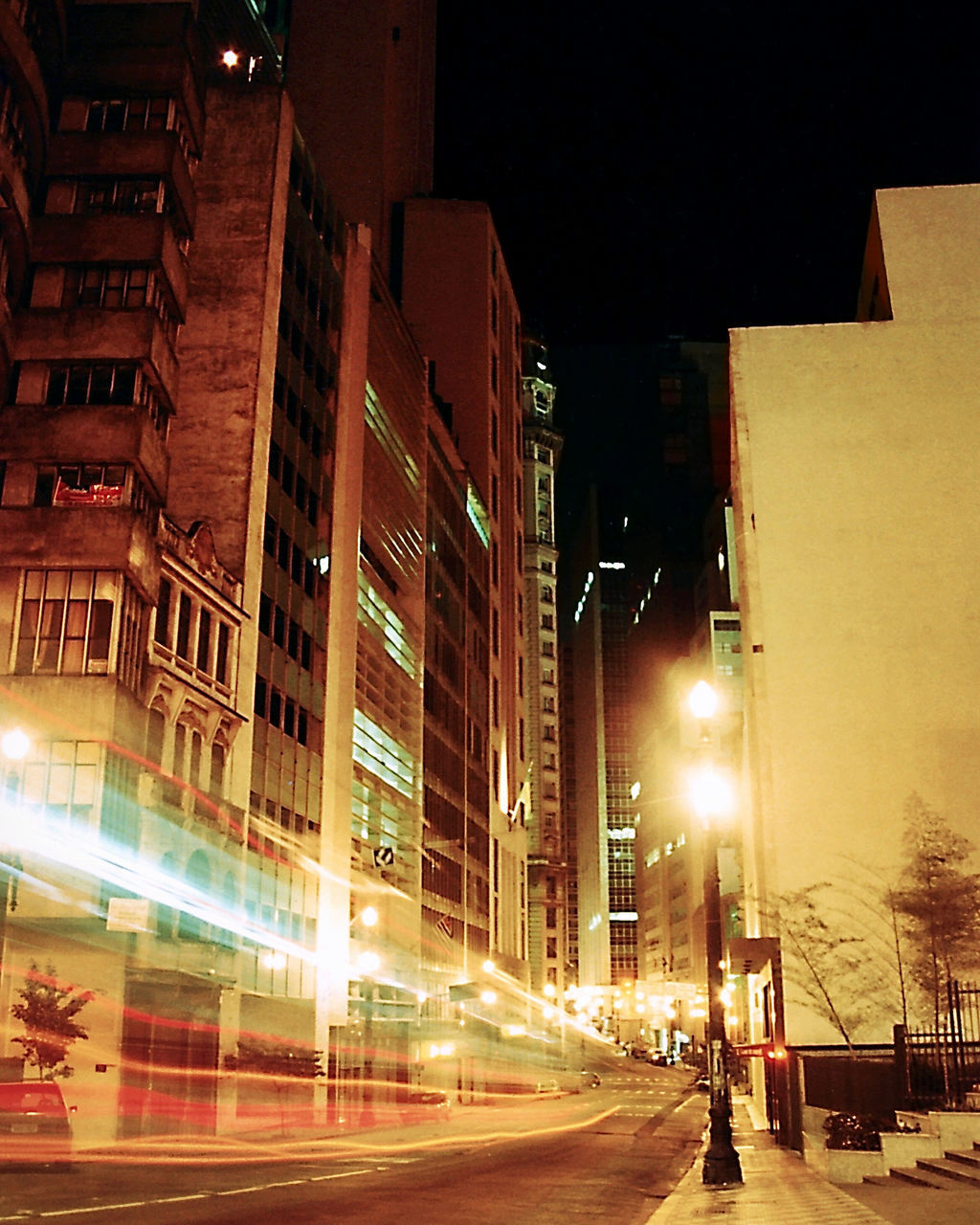 ILLUMINATED STREET AMIDST BUILDINGS AT NIGHT