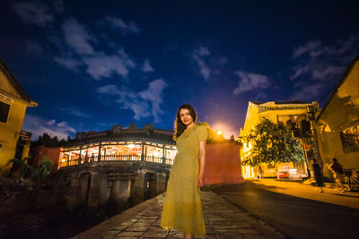 Woman against illuminated buildings in city at night