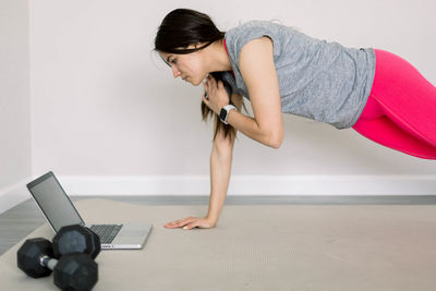 Side view of young woman exercising in gym