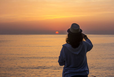 Rear view of man standing on beach during sunset