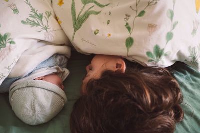 High angle view of mother and son sleeping on bed at home