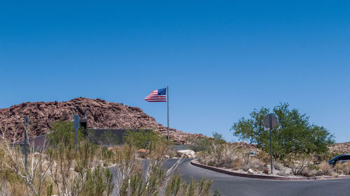 View of flag on road against clear blue sky