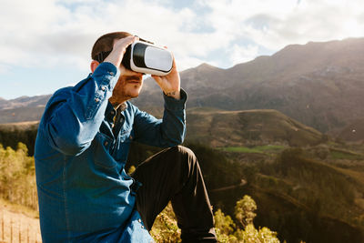 Rear view of man photographing on mountain against sky