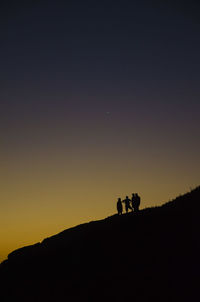 Silhouette people on field against sky during sunset