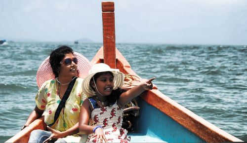 Daughter with mother pointing in boat on sea