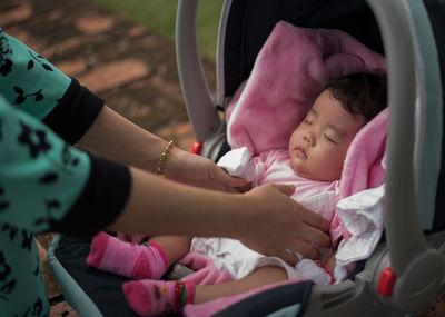 Cropped hands of mother keeping daughter in baby stroller