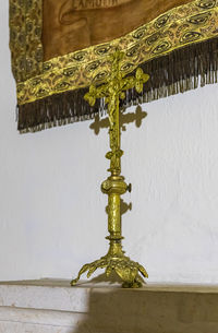 Close-up of cross on table against wall