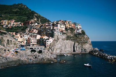 View of town by sea against clear blue sky