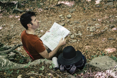 Man reading map while sitting in forest