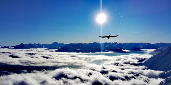 Airplane flying over snowcapped mountains against blue sky