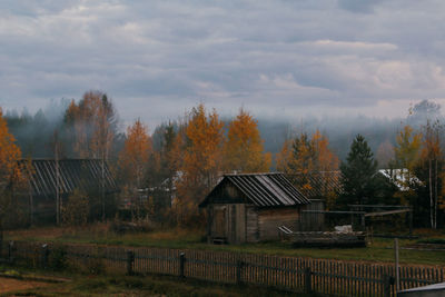 Houses and trees on field against sky