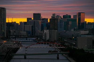 Illuminated buildings in city against sky at sunset