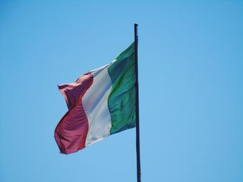 Low angle view of flag waving against blue sky