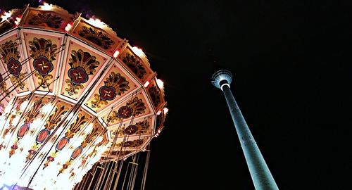 Low angle view of illuminated carousel against sky at night