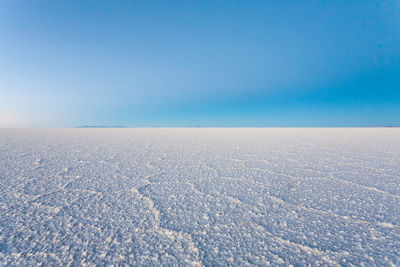 Scenic view of snow covered landscape against clear blue sky