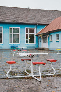 Empty chairs and tables against house in city