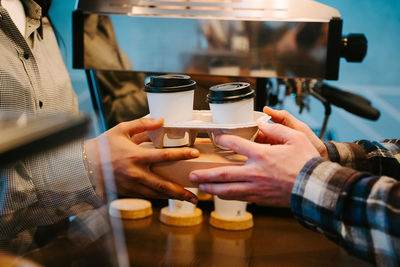 Close-up of hands holding takeaway coffees