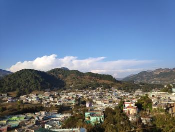 Townscape by mountains against blue sky