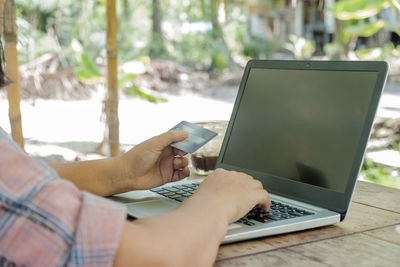 Midsection of man using mobile phone on table